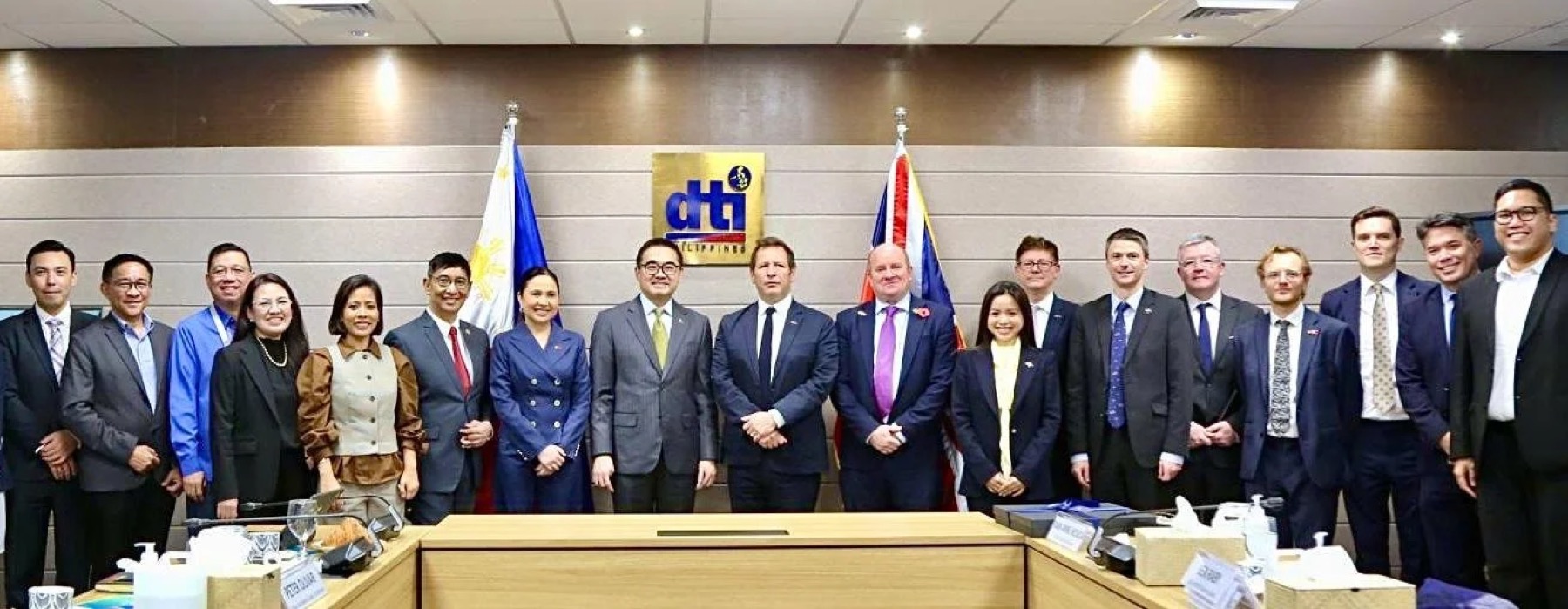 A delegation photographed between the Philippine and British flags at the Department of Trade and Industry